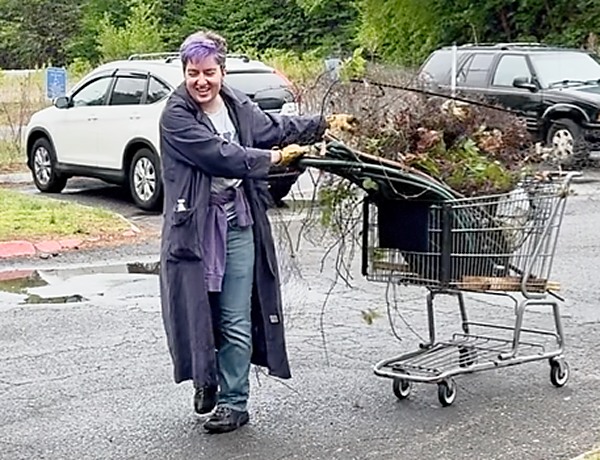 woman pushing shopping cart full of debris