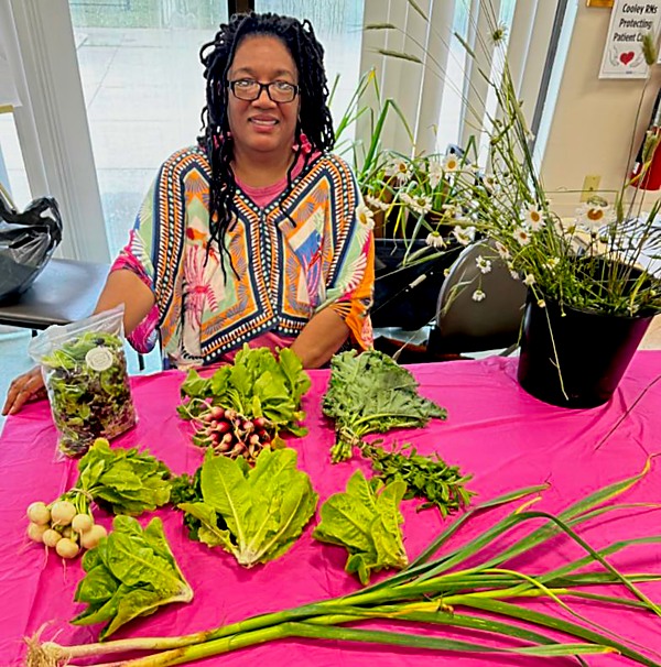 woman seated, behand table with fresh vegetables