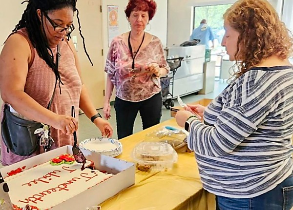 woman cutting cake, while others watch