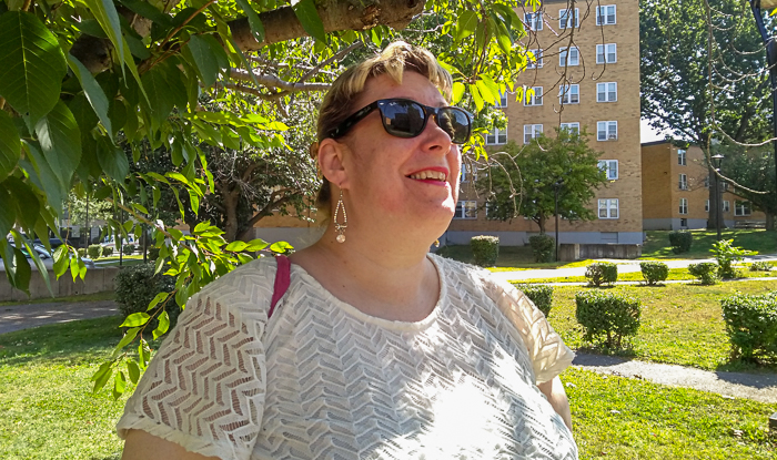 Lynn Costello under green tree in apartment yard