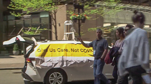 Van displays banner "Give Us Care, not COVID"