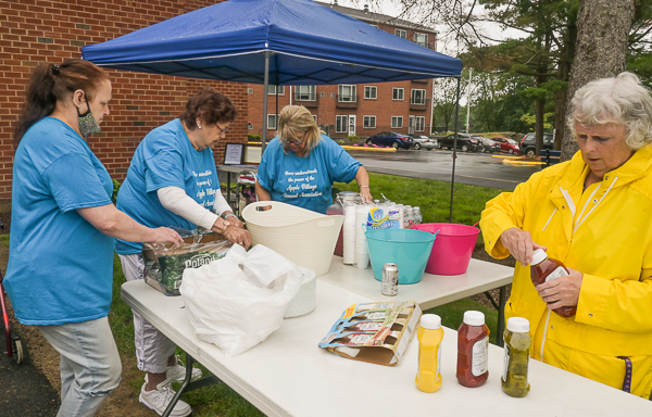 The hosts prepare to grill hot dogs with all the fixings.